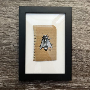 Black and white gouache ink illustration of a bee done on cardboard. Framed in black.